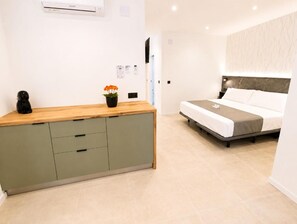 Un dormitorio con cama, mesita de noche, una pequeña planta en maceta y aire acondicionado de pared.