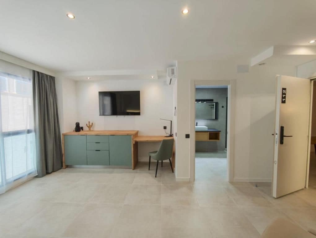 Een moderne hotelkamer met een kitchenette, bureau en televisie.