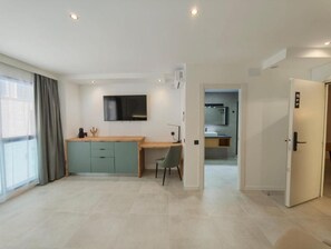 Una habitación de hotel moderna con kitchenette, un escritorio y un televisor.