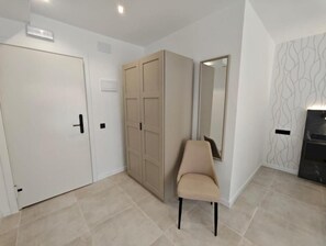 Una habitación con armario, una silla, un espejo y un papel tapiz estampado.