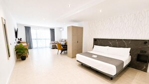 Quarto de hotel moderno com cama, escrivaninha, cadeira e guarda-roupa.