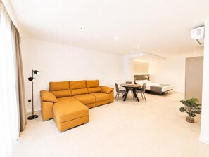 Una sala moderna con un sofá modular, una mesa de comedor con sillas y una pequeña planta en maceta.