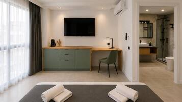 Une chambre d’hôtel équipée d’un lit, d’un bureau, d’une chaise, d’une télévision et d’un espace douche.