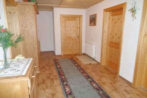 Ein Flur mit Holztüren, einem Heizkörper und einem gemusterten Teppich.