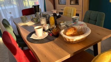 Uma mesa de café da manhã com um cesto de croissants, uma xícara de café e diversos itens para o café da manhã.