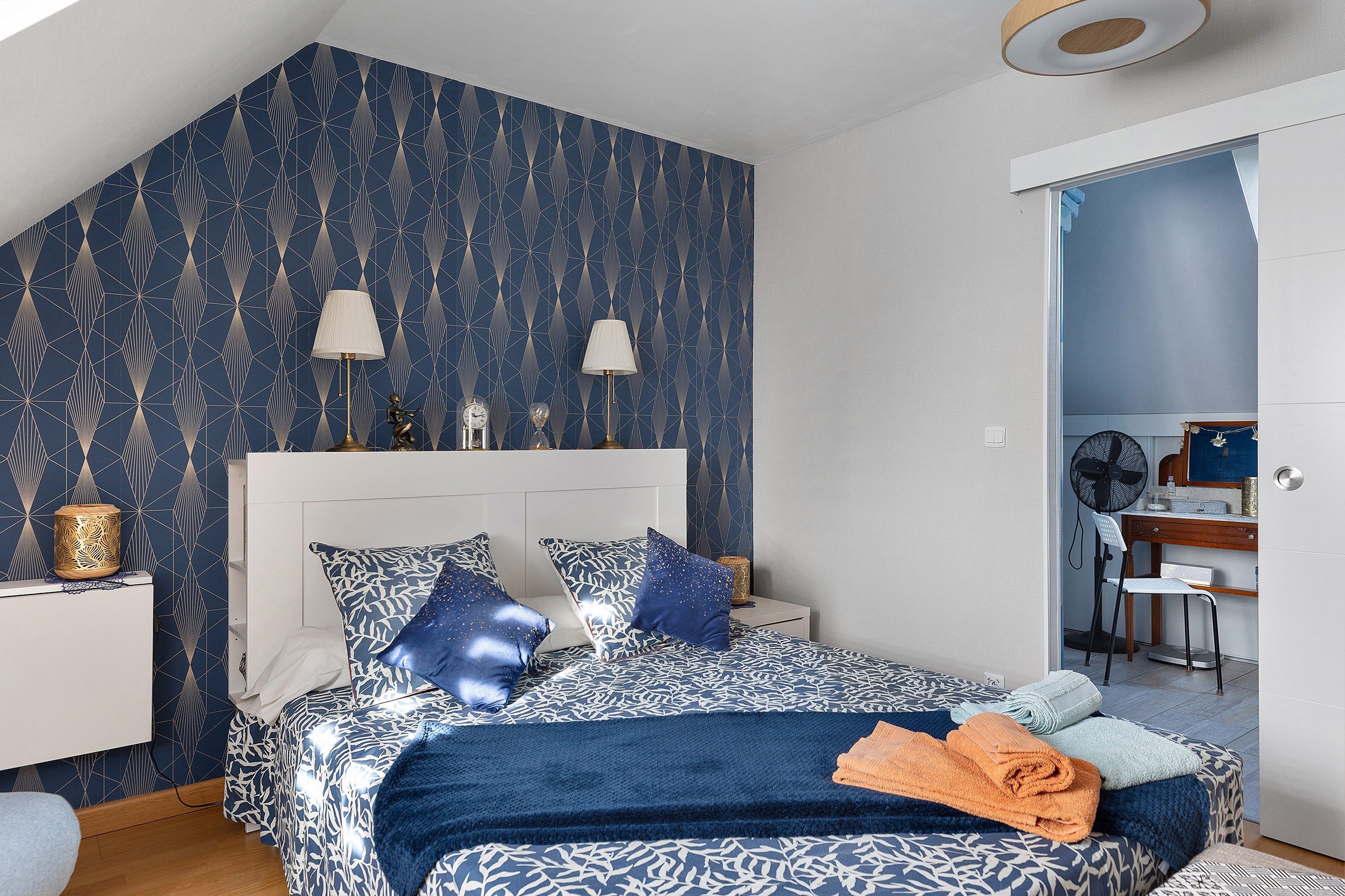 Une chambre à coucher avec un lit, deux lampes de chevet, une horloge et un miroir.