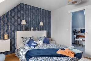 A bedroom with a bed, two bedside lamps, a clock, and a mirror.