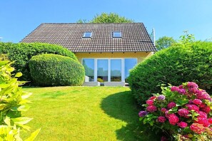 A house with a tiled roof, a front porch, and a well-maintained lawn. - Holiday home in Lindau with swimming pool (Lindau)