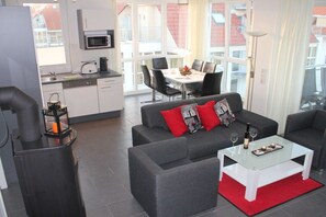 A modern living room with a sofa, a glass coffee table, and a fireplace. - Holiday apartment with 2 bedrooms (Großenbrode)