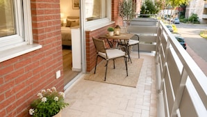 A balcony with a table and chairs, a potted plant, and a view of the street. - Pulheim Living 2 (Pulheim)