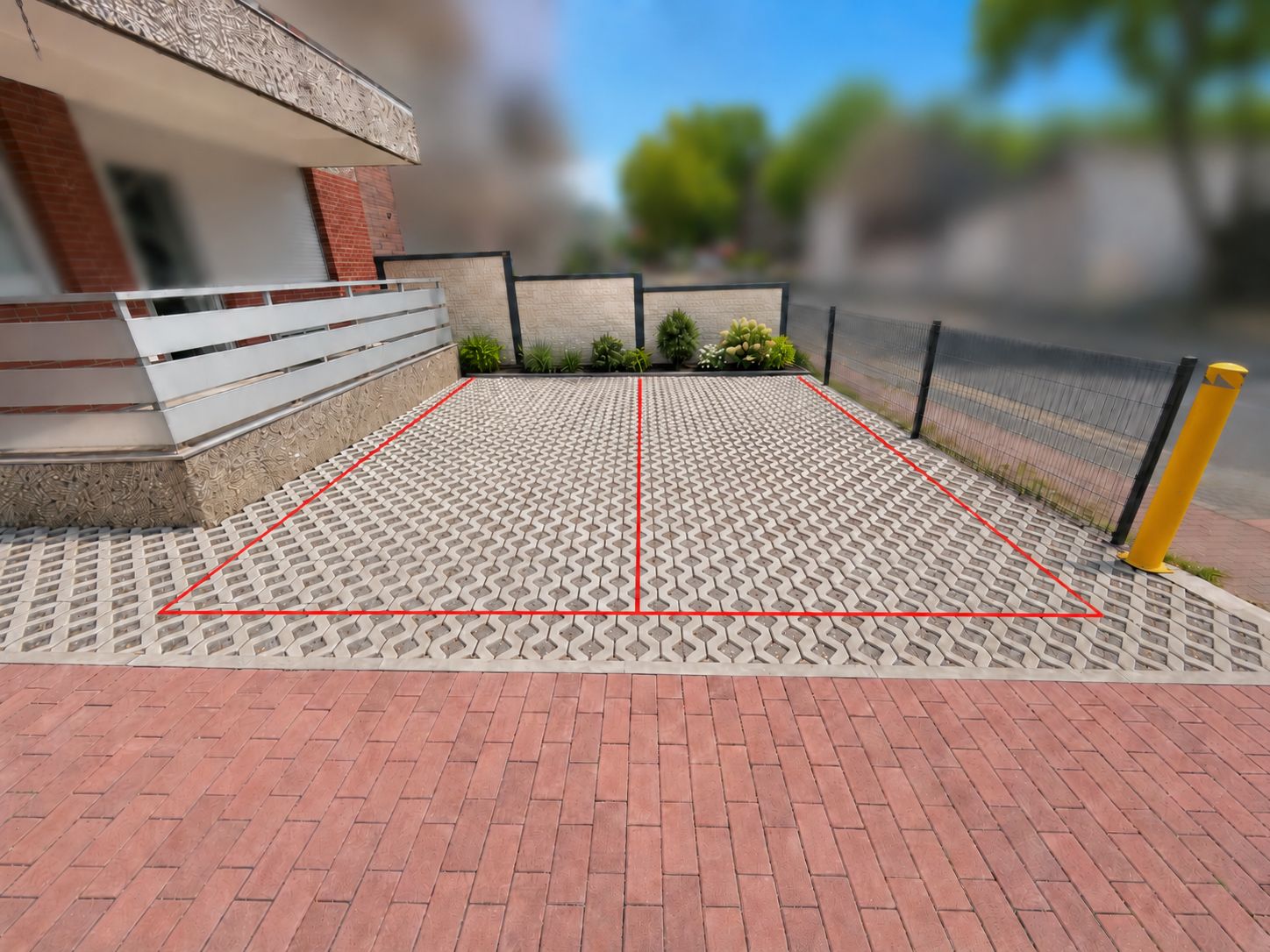 A paved area with a geometric pattern, bordered by a fence and a building with a modern design.