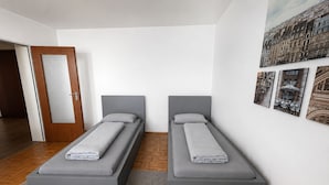 A modern bedroom with two single beds, a wooden door, and a wall with framed pictures. - Pulheim Living 2 (Pulheim)