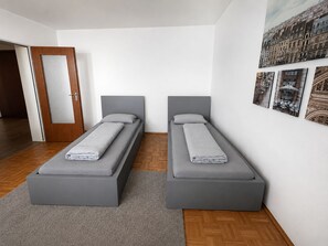 A modern bedroom with two single beds, a wooden door, and a wall with framed pictures. - Pulheim Living 2 (Pulheim)