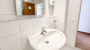 A bathroom with a white sink, a mirror, and a towel dispenser. - Pulheim Living 2 (Pulheim)