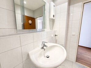 A bathroom with a white sink, a mirror, and a towel dispenser. - Pulheim Living 2 (Pulheim)