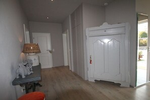 A hallway with a white door, a lamp, and a small table with a bear figurine. - Holiday home with 2 bedrooms (Heiligenhafen)