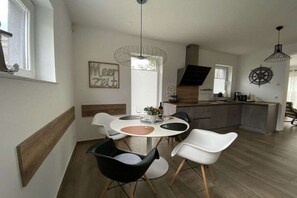 Eine moderne Küche mit Essbereich, Holzboden und einer Pendelleuchte.