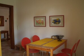 A dining area with a wooden table, red chairs, and two framed floral paintings on the wall. - Holiday home with 2 bedrooms (St. Michaelisdonn)