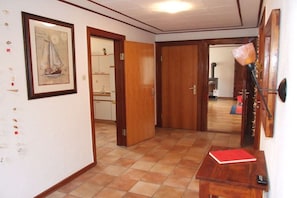 A hallway with a wooden door, a framed picture on the wall, and a red notebook on a small table. - Holiday home with 2 bedrooms (St. Michaelisdonn)