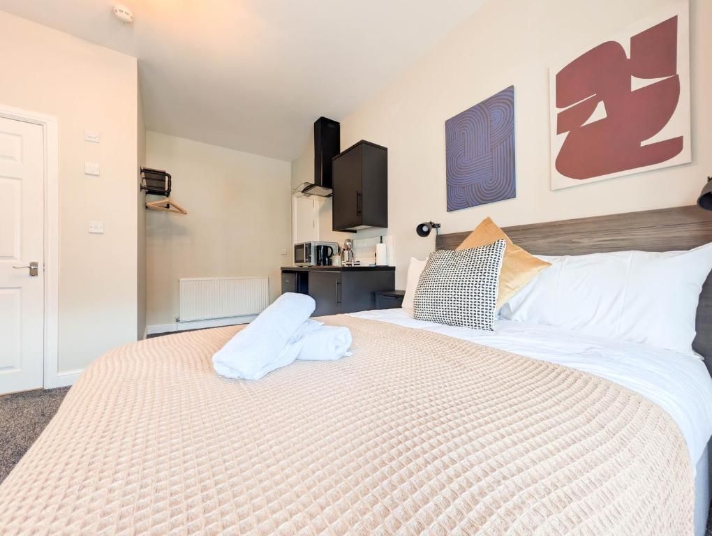 A hotel room with a bed, a bedside table, a mirror, and artwork on the wall.