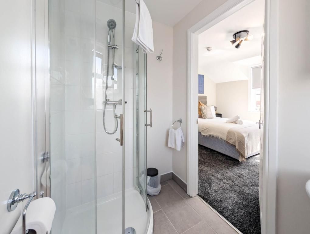 A modern bathroom with a glass-enclosed shower, a toilet, and a visible towel rack.
