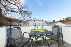 A balcony with two chairs and a table, a bottle of water, and a glass. - 22, Residence Dünenstraße (Binz)