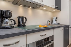 A modern kitchen with a coffee maker, a toaster, and a cutting board with orange slices. - 22, Residence Dünenstraße (Binz)