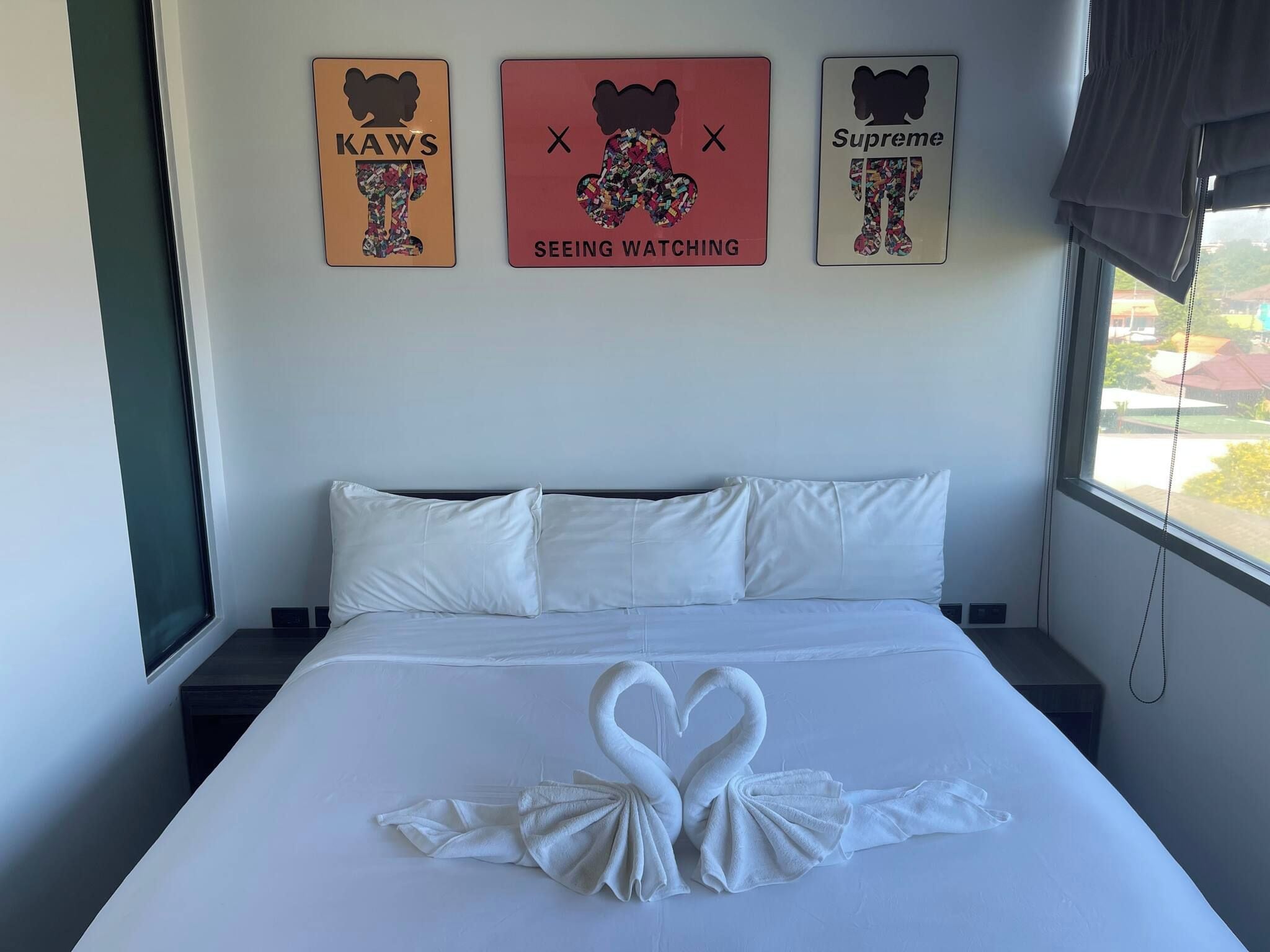 Une chambre d’hôtel avec un lit, des oreillers et trois œuvres d’art murales.