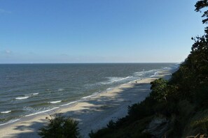 Ein Strand mit Wellen, sandigem Ufer und blauem Himmel.