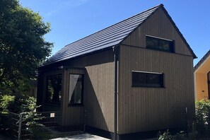 Ein modernes, zweistöckiges Gebäude mit Satteldach und einem kleinen Balkon.
