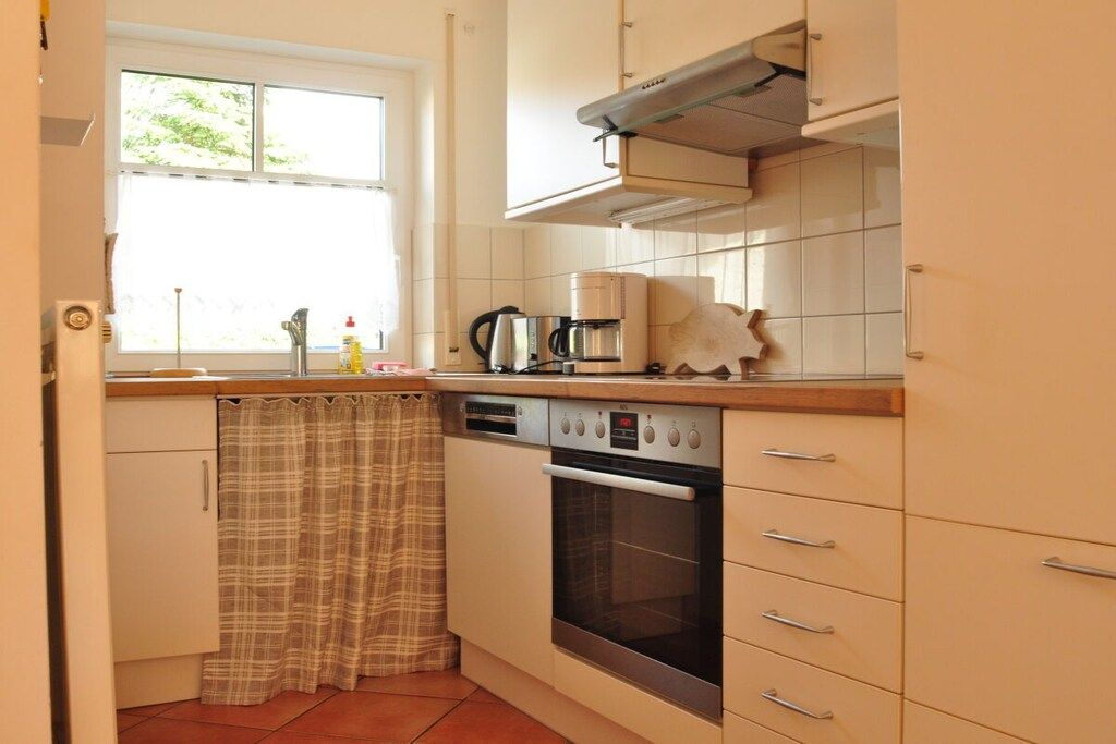A compact kitchen with a window, a coffee maker, an oven, and a dishwasher.