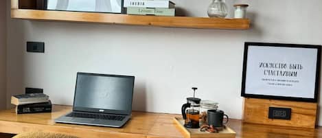 A workspace with a laptop, books, a wooden desk, a chair, and decorative items including a framed quote and a vase with flowers.