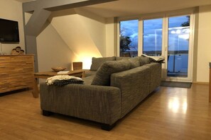 Ein modernes Wohnzimmer mit einer Couch, einer Holzkommode und einem Fernseher.