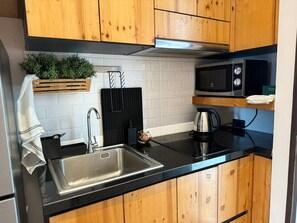 A modern kitchen with a stainless steel sink, a kettle, a microwave, and wooden cabinets. - Quiet Sea-view Studio, Walk to Nai Harn Beach (Rawai)