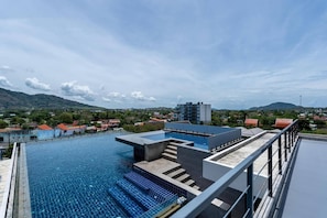 A rooftop swimming pool with clear blue water, surrounded by buildings and a mountainous landscape. - Quiet Sea-view Studio, Walk to Nai Harn Beach (Rawai)