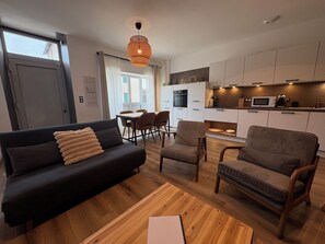 En moderne stue med en sofa, lænestole og et spiseområde med stole og bord.