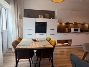 Et tidssvarende køkken med hvide skabe, en sort ovn og en mikroovn.