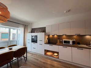 A modern kitchen with white cabinets, a microwave, and a dining area with a table and chairs.