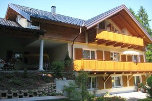 Ein zweistöckiges Haus mit Balkon, überdachter Veranda und Garten.