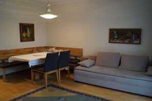 Ein Zimmer mit Esstisch, Stühlen, einer Couch und zwei Bildern an den Wänden.