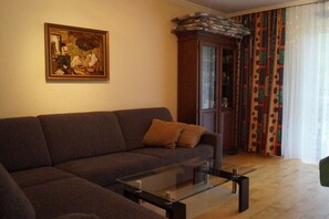 Ein Wohnzimmer mit einer Couch, einem Glastisch, einem Schrank und einem Gemälde an der Wand.