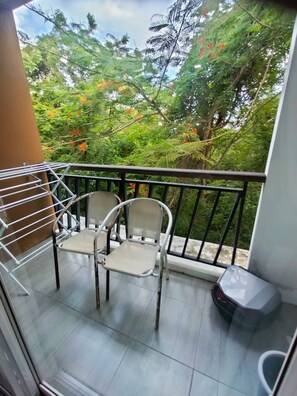 A balcony with two chairs, a metal drying rack, and a small trash bin. - Quiet & Cozy 1br, Pool, Rawai, Walk to Gyms (Rawai)