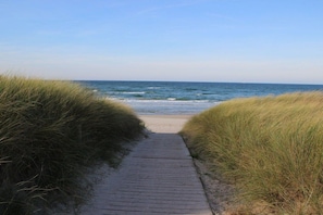 Ein Holzweg, der zu einem Strand mit Blick aufs Meer führt.