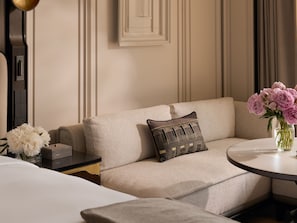 A hotel room with a sofa, a small table with a vase of flowers, and a bed. - The Langham, Custom House, Bangkok (Bangkok)