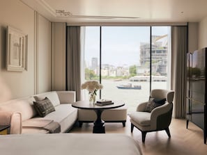 A modern hotel room with a large window, a sofa, a chair, a small table, and a bed. - The Langham, Custom House, Bangkok (Bangkok)