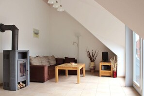 A modern living room with a fireplace, a sofa, a coffee table, and a television on a stand. - "At the Old Smallholder's Farm" (Ostseebad Prerow)