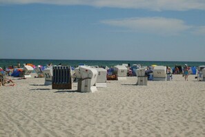 A beach with numbered beach huts and umbrellas. - "At the Old Smallholder's Farm" (Ostseebad Prerow)