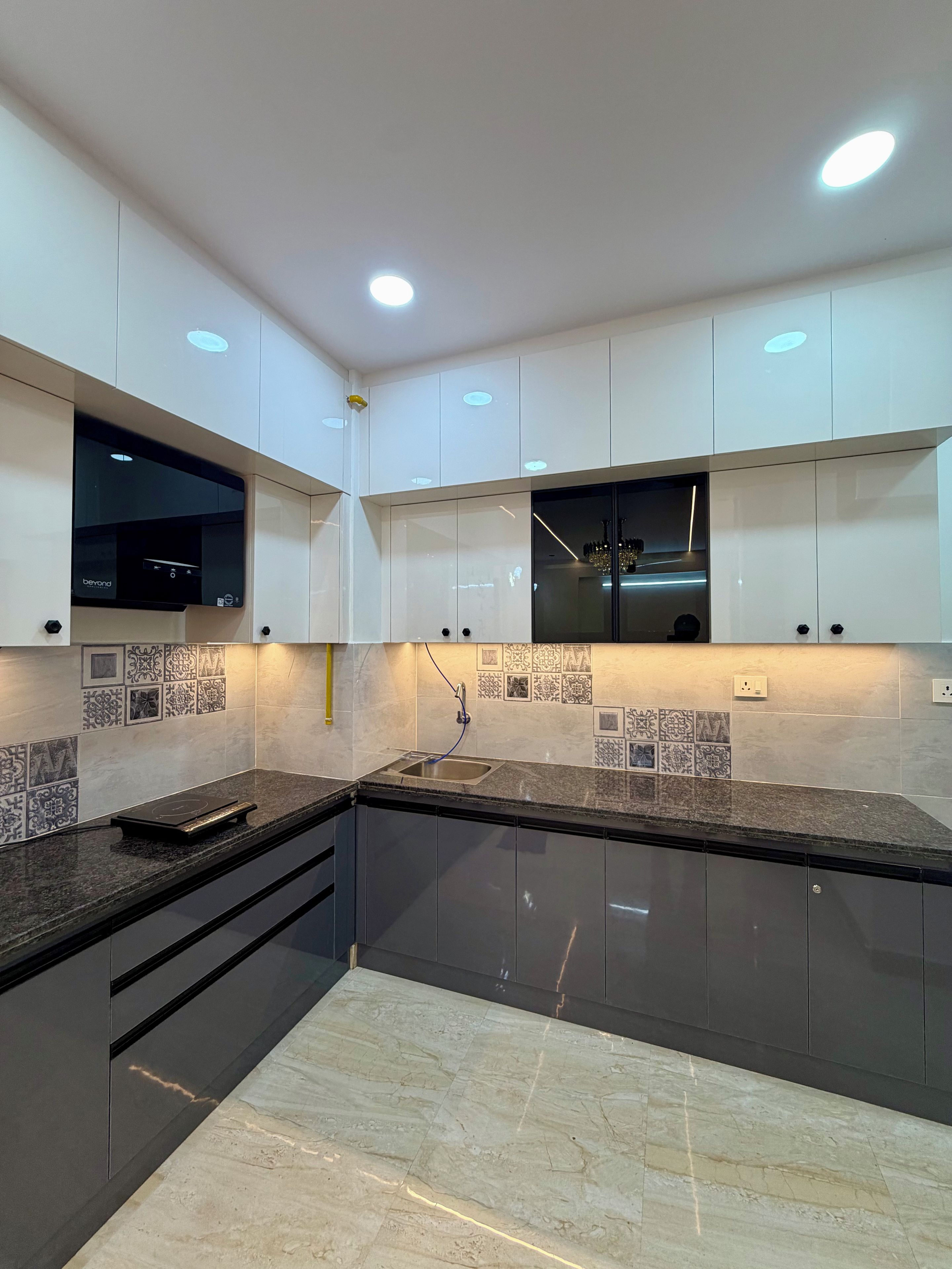 A modern kitchen with dark cabinetry, a built-in oven, and patterned backsplash tiles.