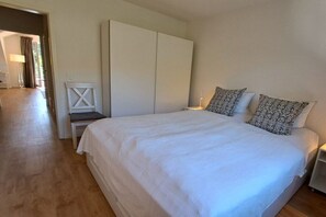A bedroom with a large bed, a wardrobe, a chair, and a nightstand. - Holiday apartment with 2 bedrooms (Ostseebad Boltenhagen)