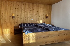 A wooden bed in a room with vertical wooden paneling and two wall-mounted lamps.